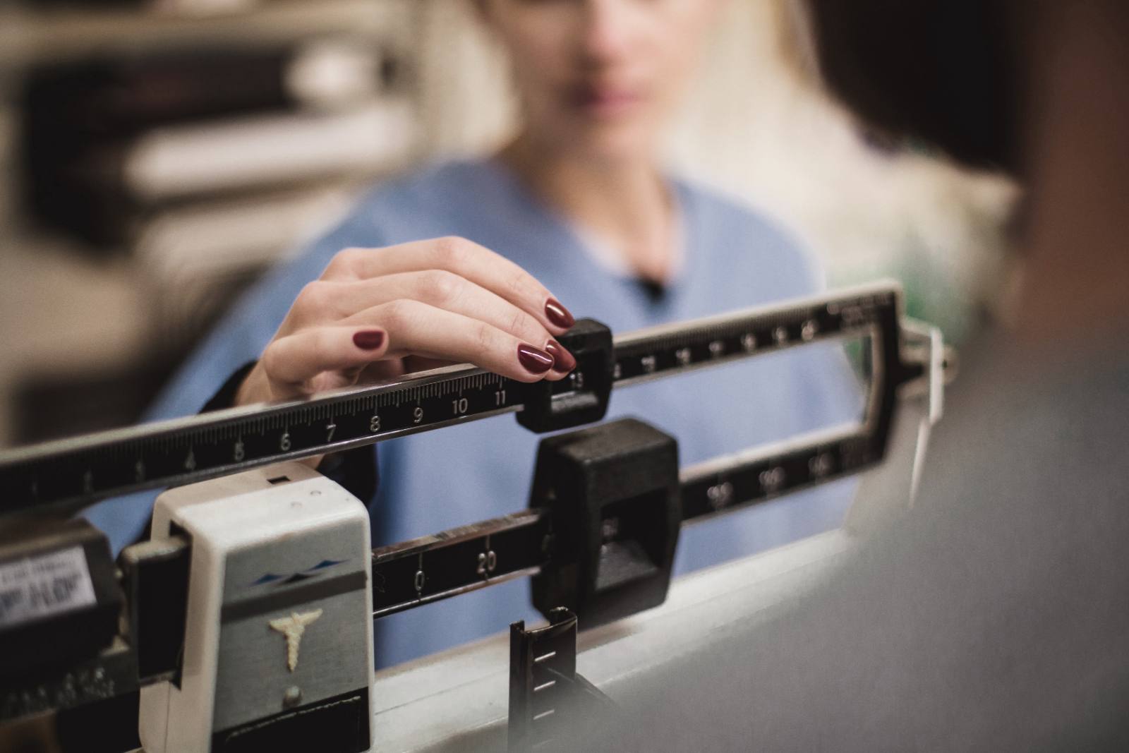 Healthcare professional adjusting a medical scale